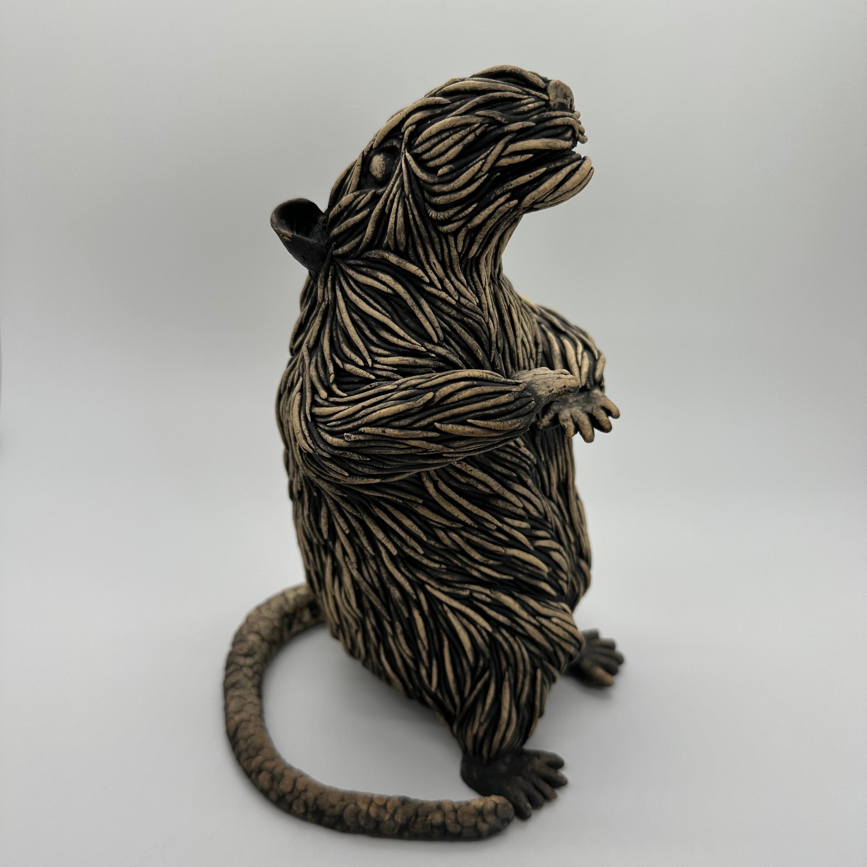Sculpture of a black and beige rat standing